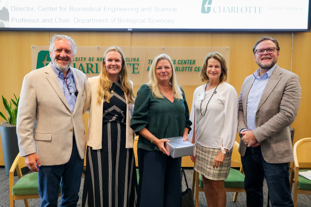 Four panelists and the moderator pose together during the 2026 Biomedical Sciences Symposium, with one person holding a gift box.